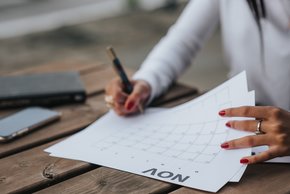 Person writing in dates on calendar
